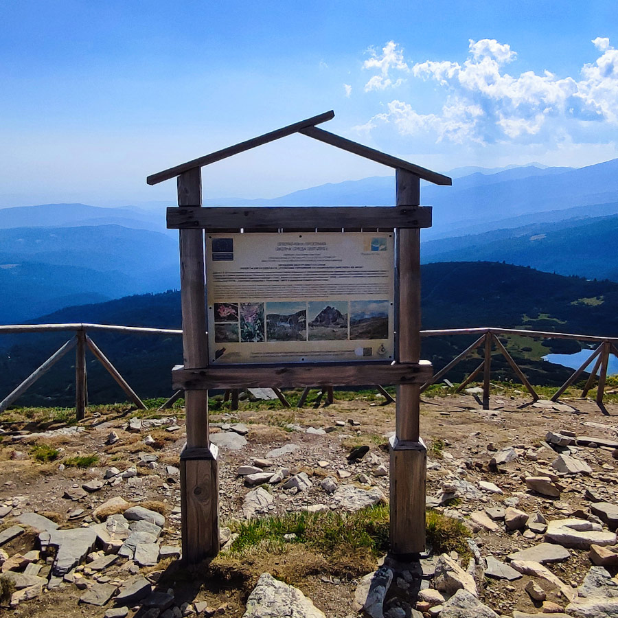 Information board at the Seven Rila Lakes viewpoint with panoramic background.