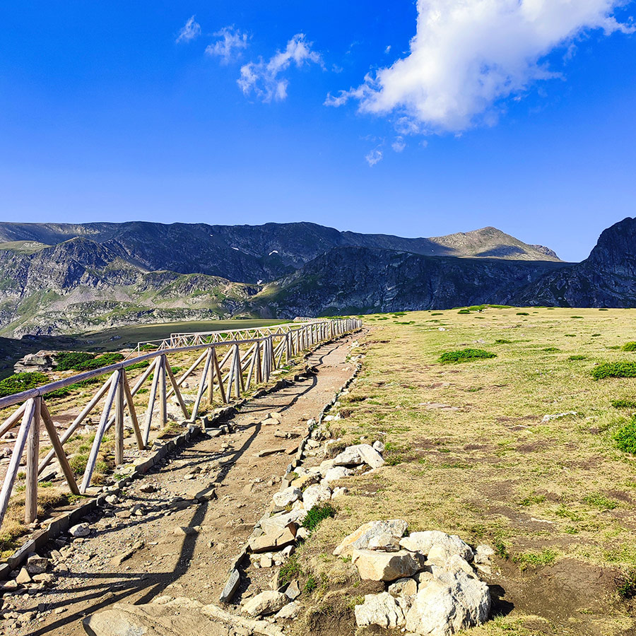 Scenic wooden railing path across alpine meadows near the Seven Rila Lakes.