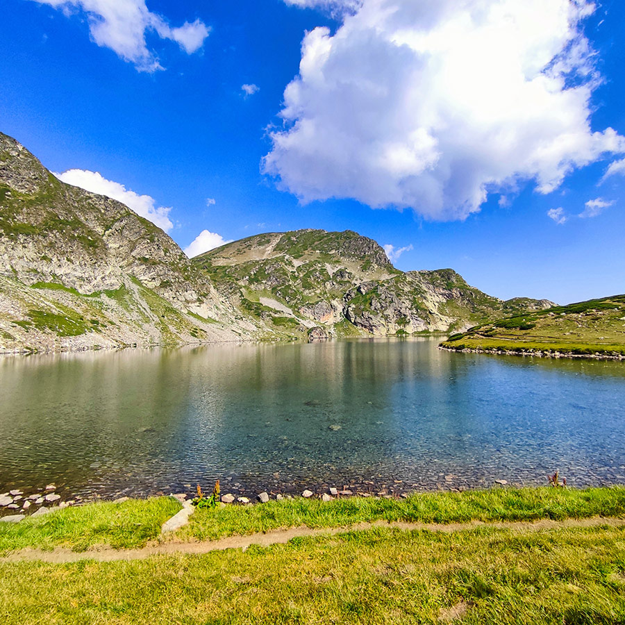 Clear alpine lake with mountains in the background at Seven Rila Lakes, Bulgaria.