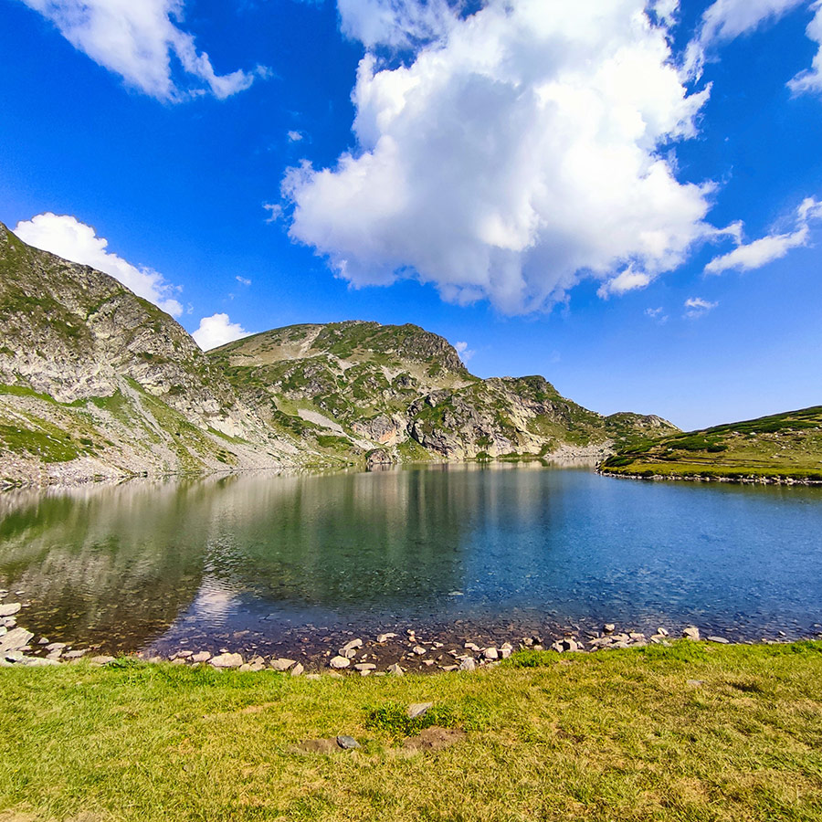 Panoramic view of the Seven Rila Lakes with crystal-clear water and surrounding green alpine meadows in Rila Mountain, Bulgaria.