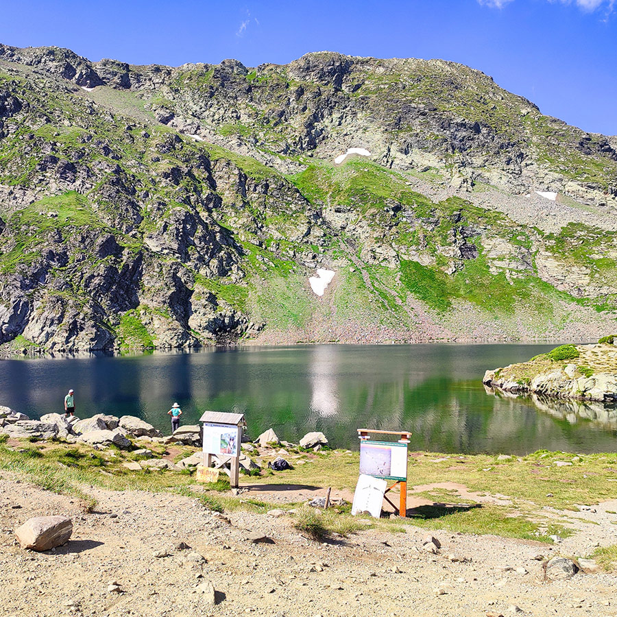 Mountain lake with trail signs at the Seven Rila Lakes, Bulgaria.