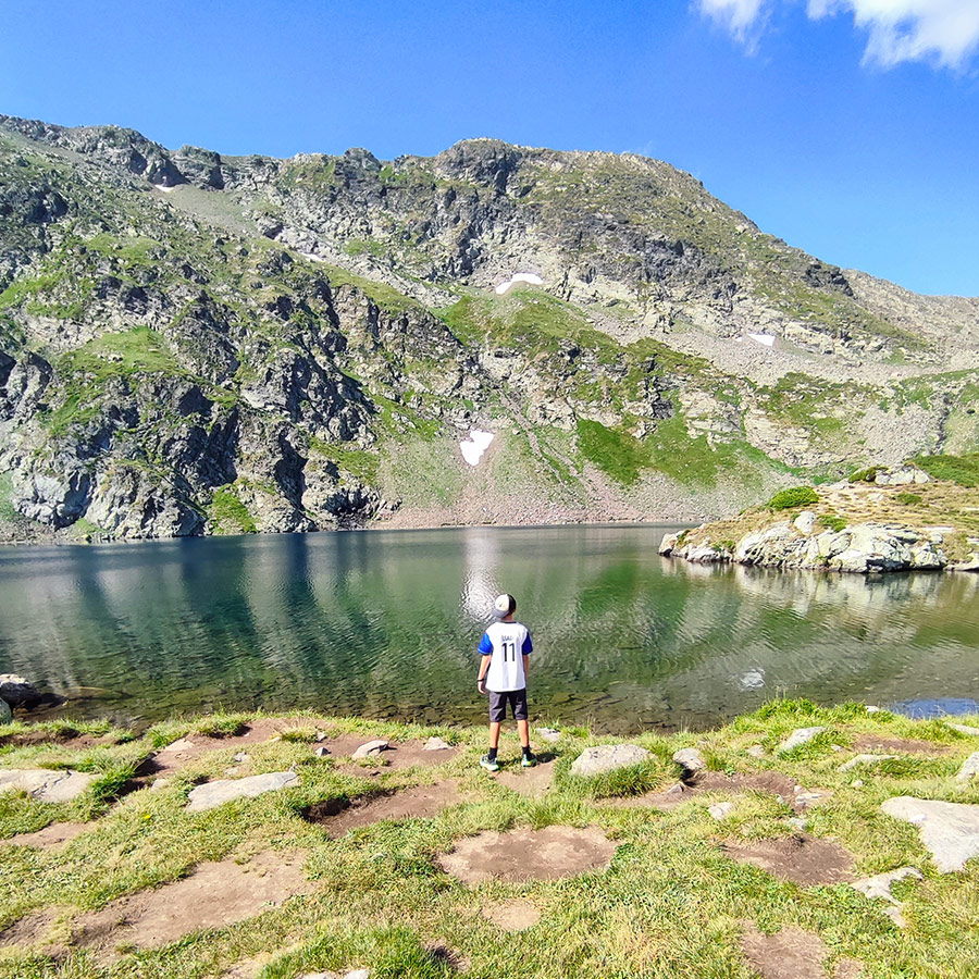 Young hiker standing at the shore of a lake in the Seven Rila Lakes, Bulgaria.