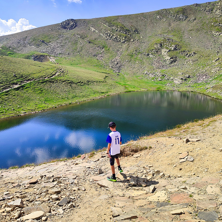 Child standing at the shore of an alpine lake, Seven Rila Lakes, Bulgaria.