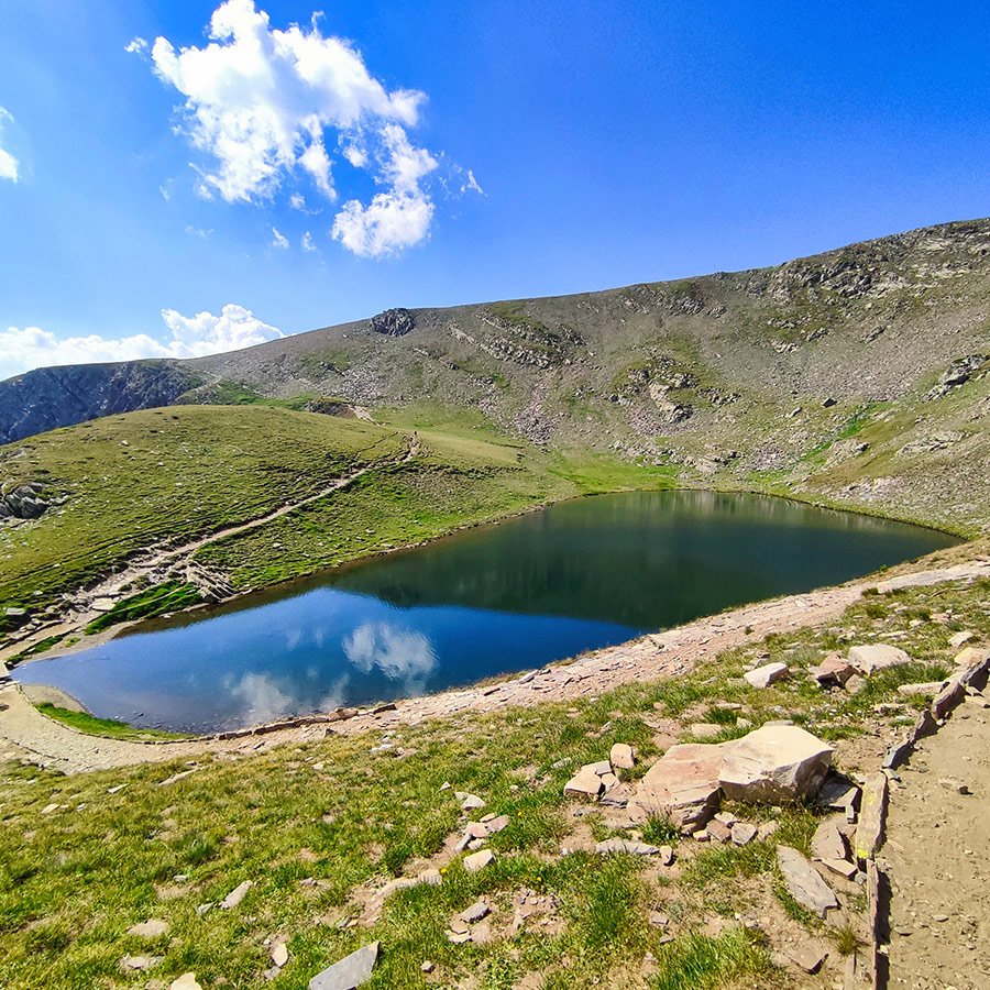 Reflective alpine lake with surrounding slopes in the Seven Rila Lakes, Bulgaria.