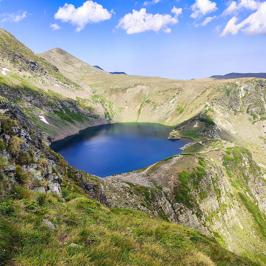 Panoramic view of the Kidney Lake, one of the Seven Rila Lakes in Bulgaria, surrounded by alpine ridges.