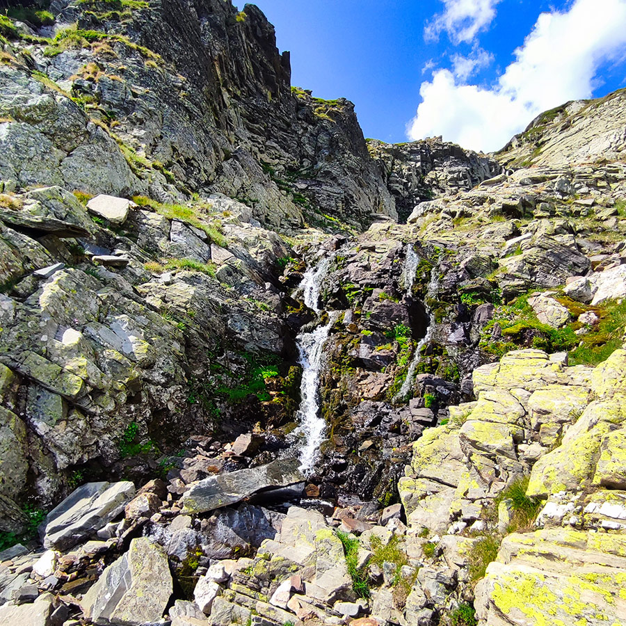 Small alpine waterfall flowing between rocky cliffs in the Seven Rila Lakes area.