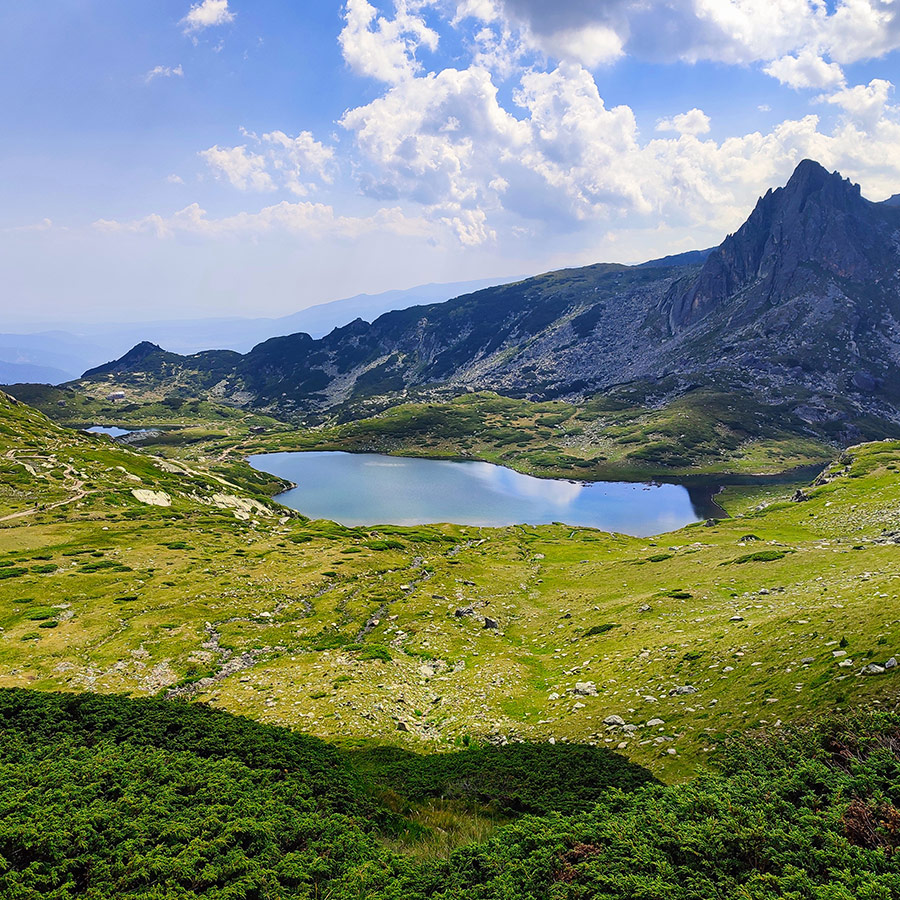 Panoramic view of an alpine lake with jagged peaks in Rila Mountain.