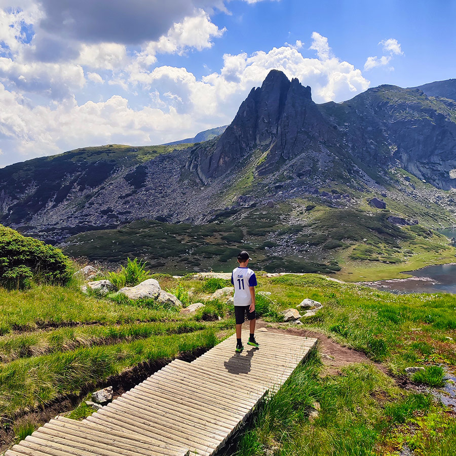 Young hiker standing on a wooden bridge near the Twin Lake, Rila Mountain.