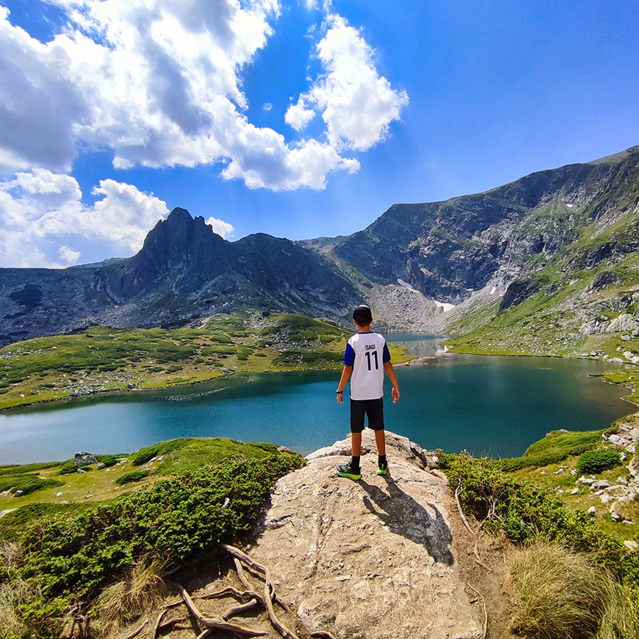 Boy standing on a rock above the Twin Lake in the Seven Rila Lakes.