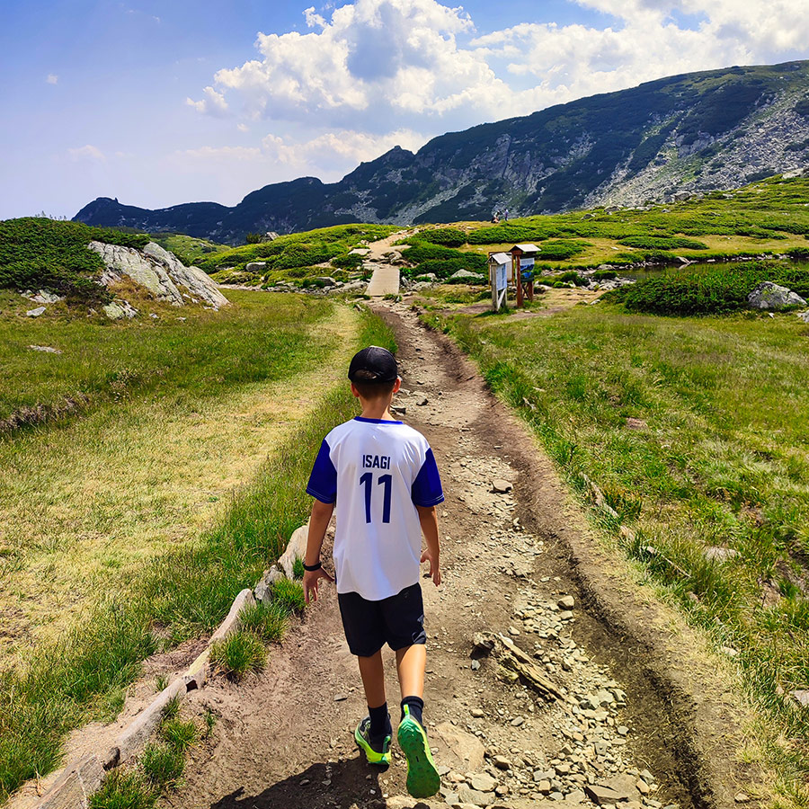 Child hiking along a dirt trail near the Seven Rila Lakes.