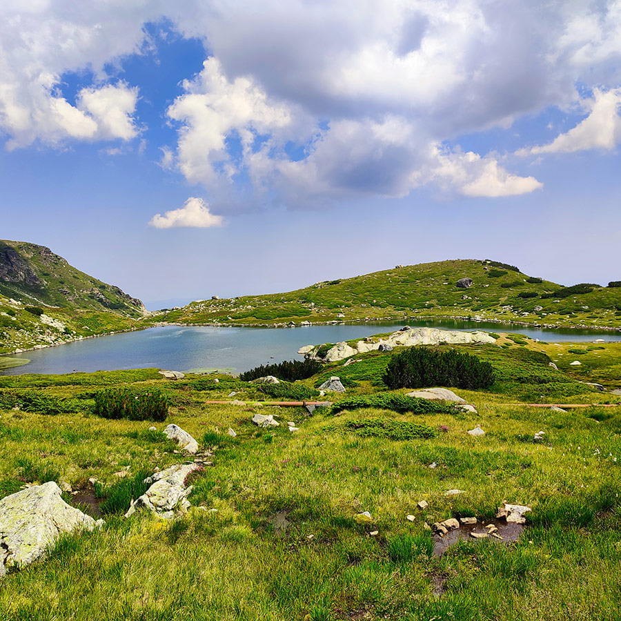 Alpine lake surrounded by lush greenery in Rila Mountain, Bulgaria.