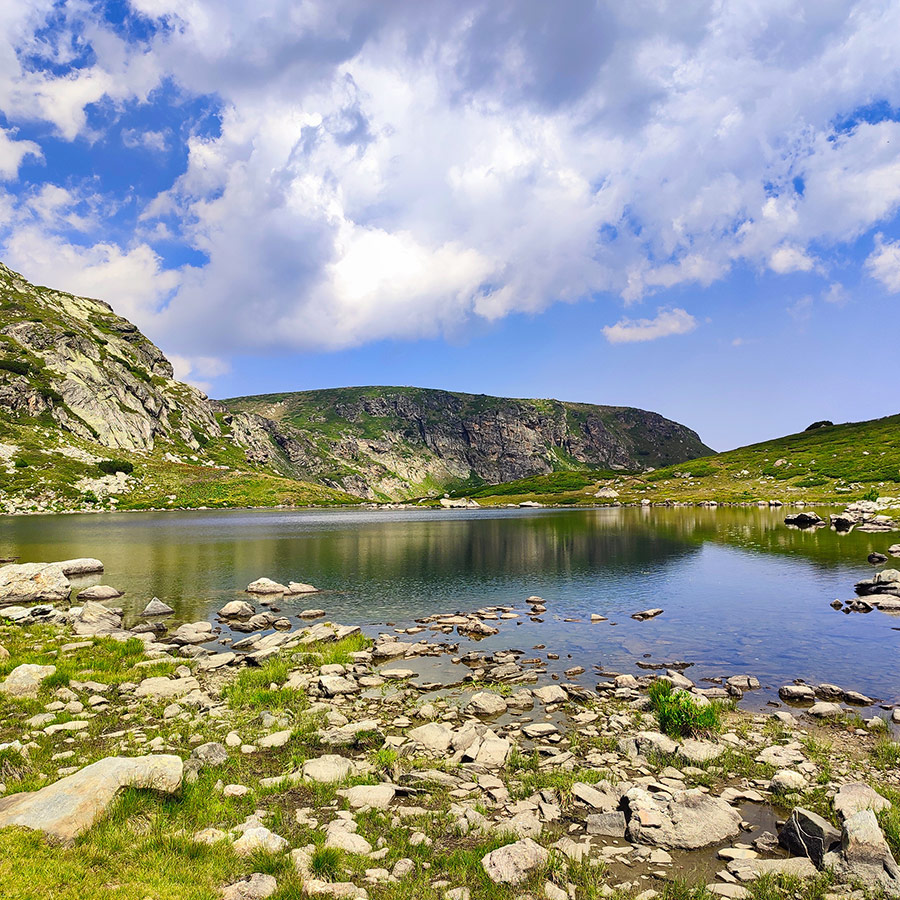 Alpine lake with rocky shoreline and steep cliffs in Rila National Park.