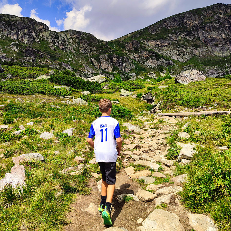 Young hiker walking along a rocky trail in the Rila Mountains towards the Seven Rila Lakes.