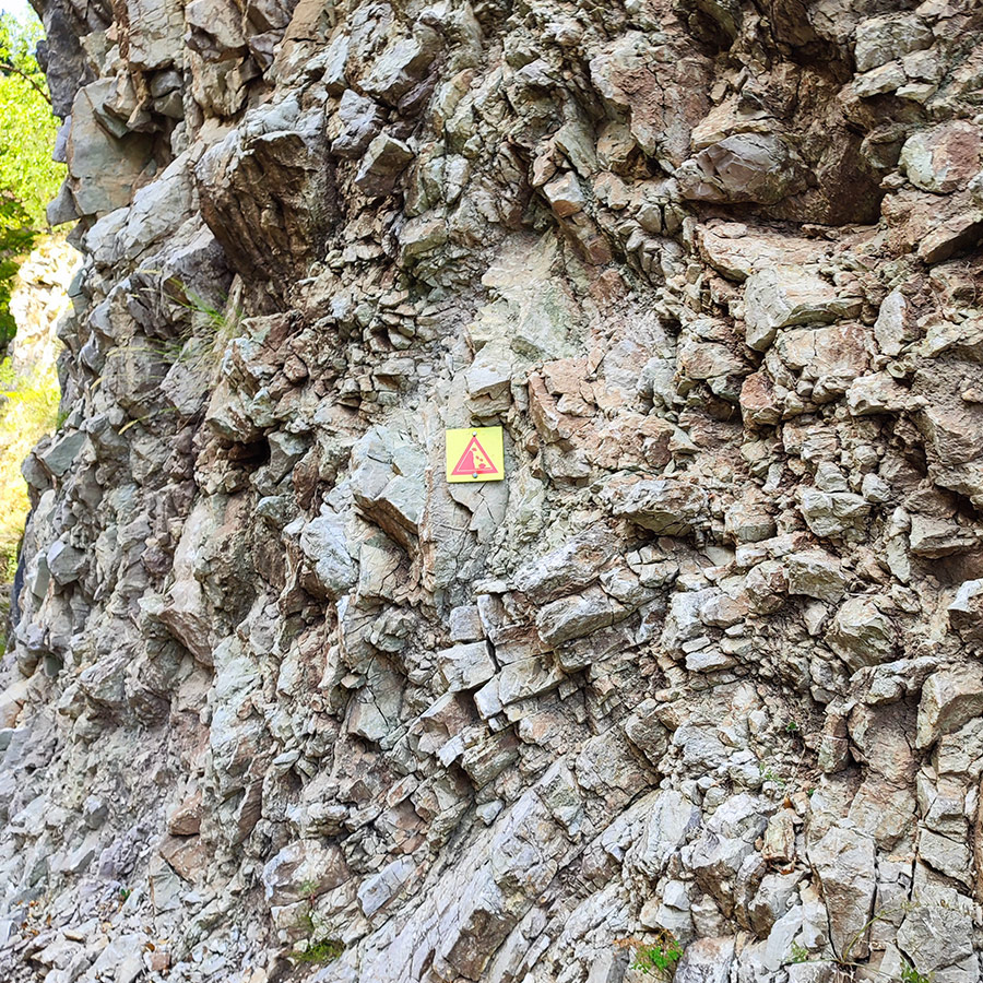 Trail danger sign on rock wall along the Anthochori Waterfall hiking path, Agrafa, Greece