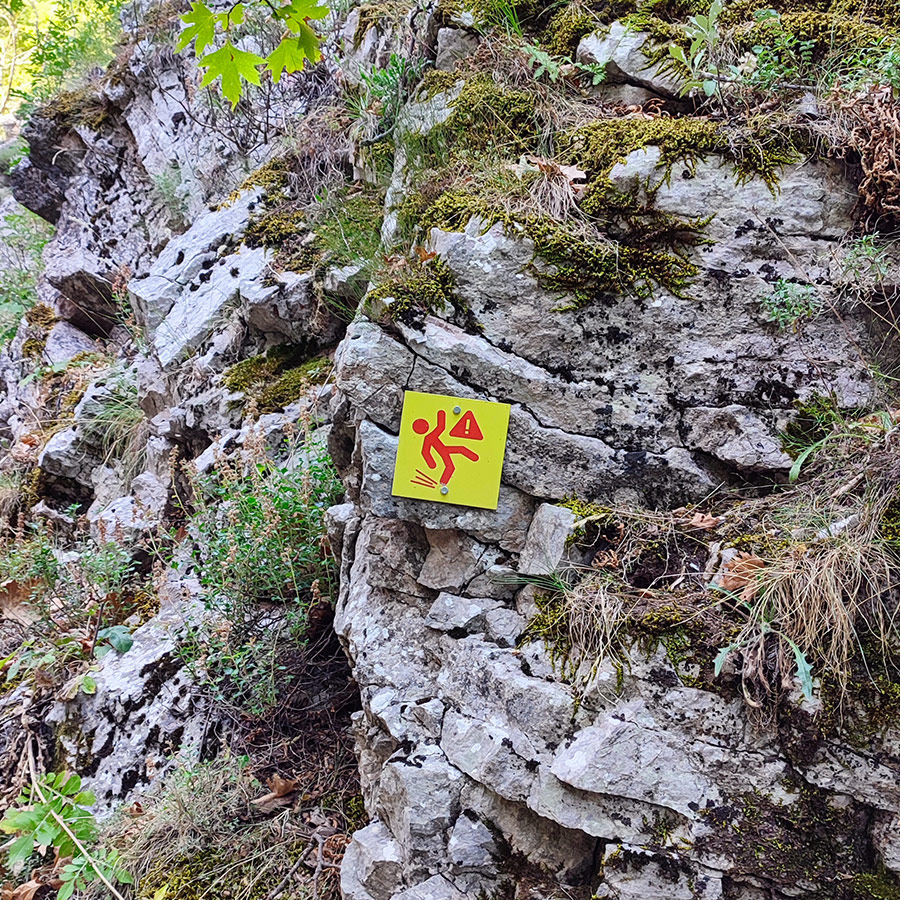 Danger sign warning of slippery rocks on Anthochori Waterfall hiking trail, Agrafa, Karditsa, Greece