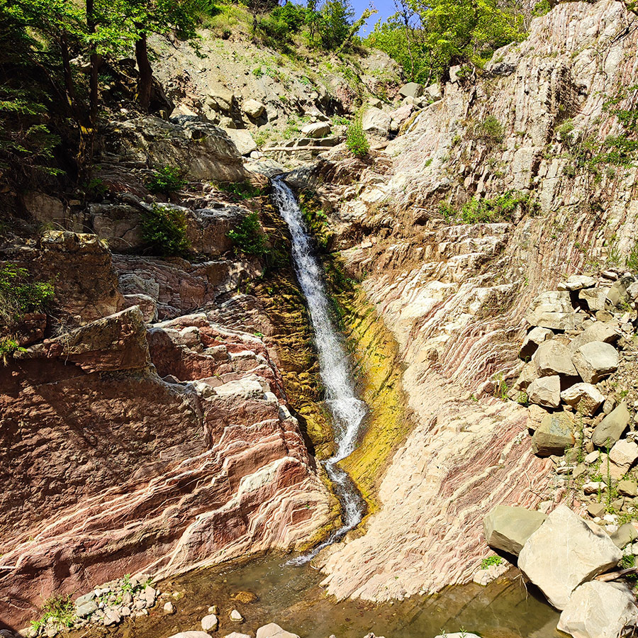 Anthochori Waterfall cascading down colorful rock layers in Agrafa, Karditsa, Greece