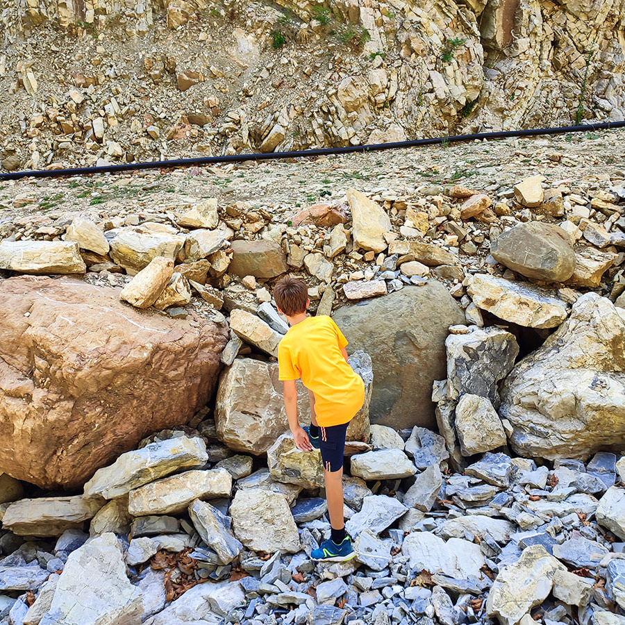 Boy climbing rocks along the hiking trail to Anthochori Waterfall, Agrafa, Greece