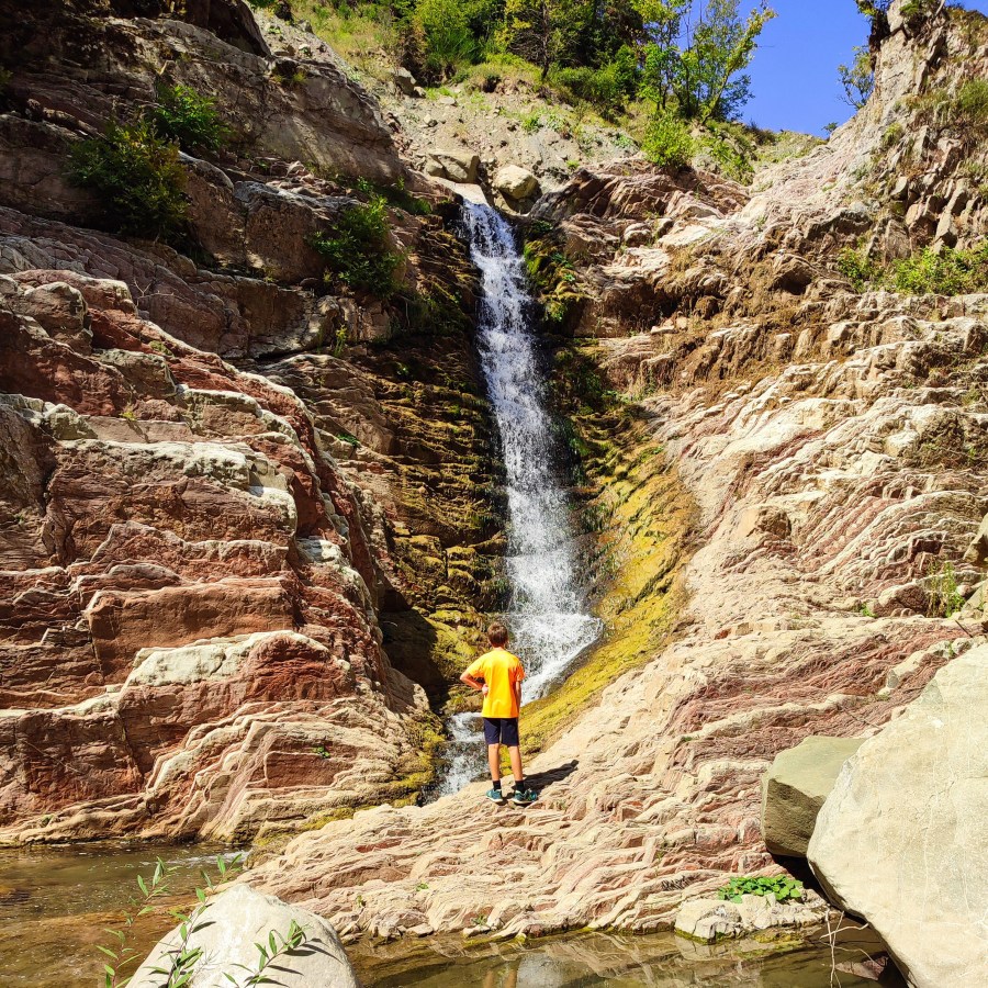 Young hiker standing at the base of Anthochori Waterfall, Agrafa, Greece