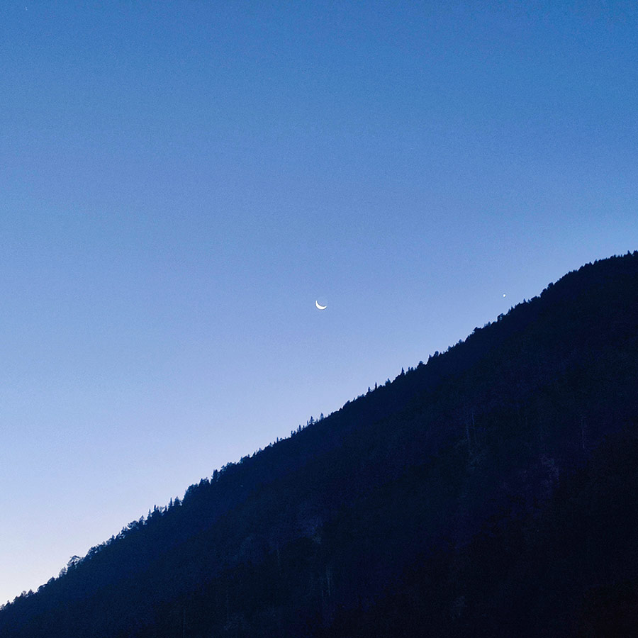 Crescent moon above the silhouette of Pirin Mountain ridge at dusk.