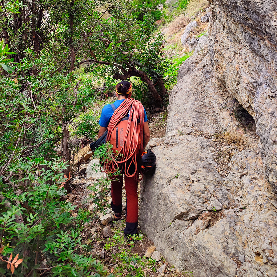 Climber navigating narrow limestone passage toward the base of Asterope on Pleiades Crag.