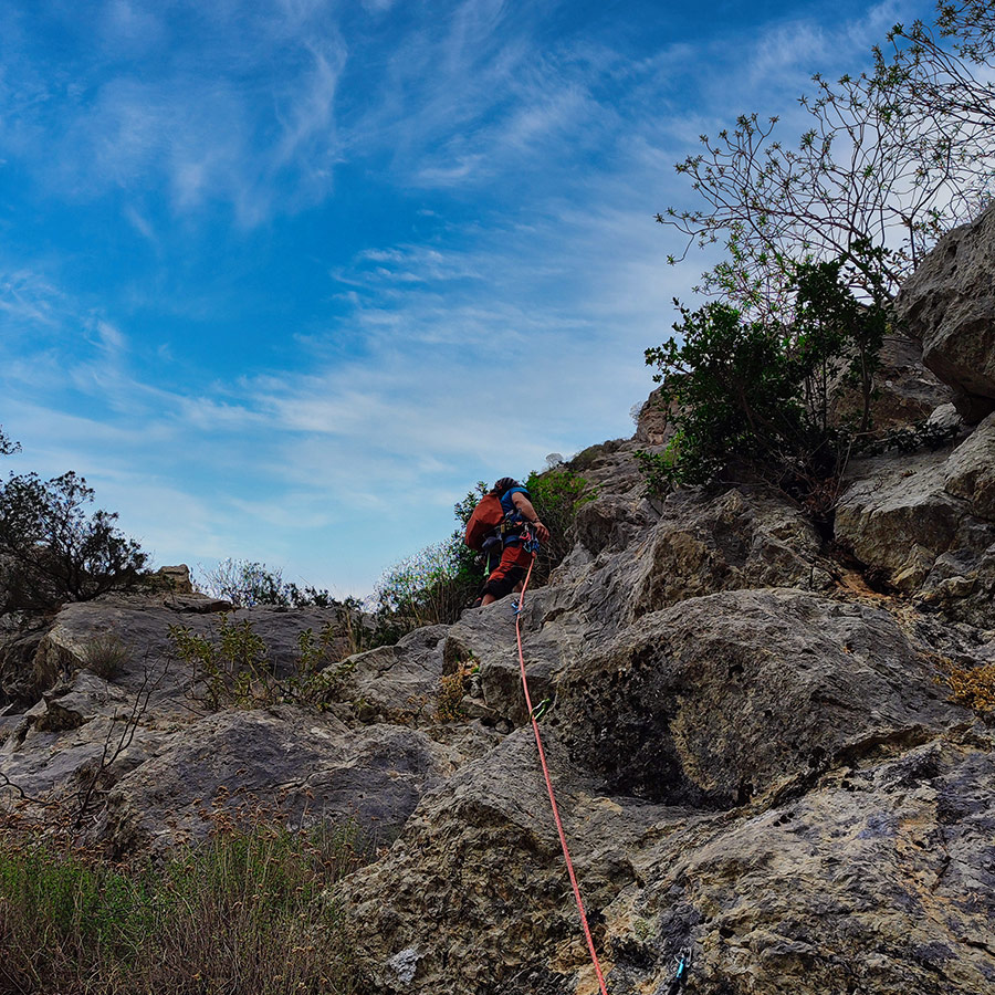 Climber leading the Asterope route with rope extended over bolted limestone in Katafyki Gorge.