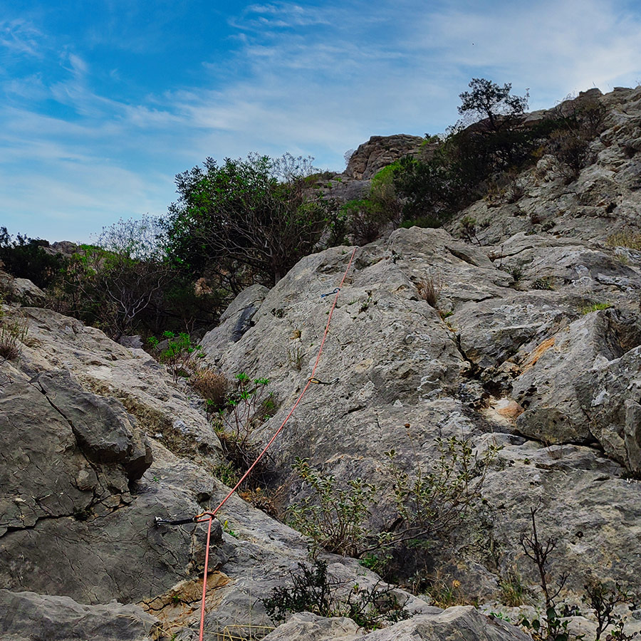 Climbing rope running along the slab section of Asterope route on Pleiades Crag, Ermioni.