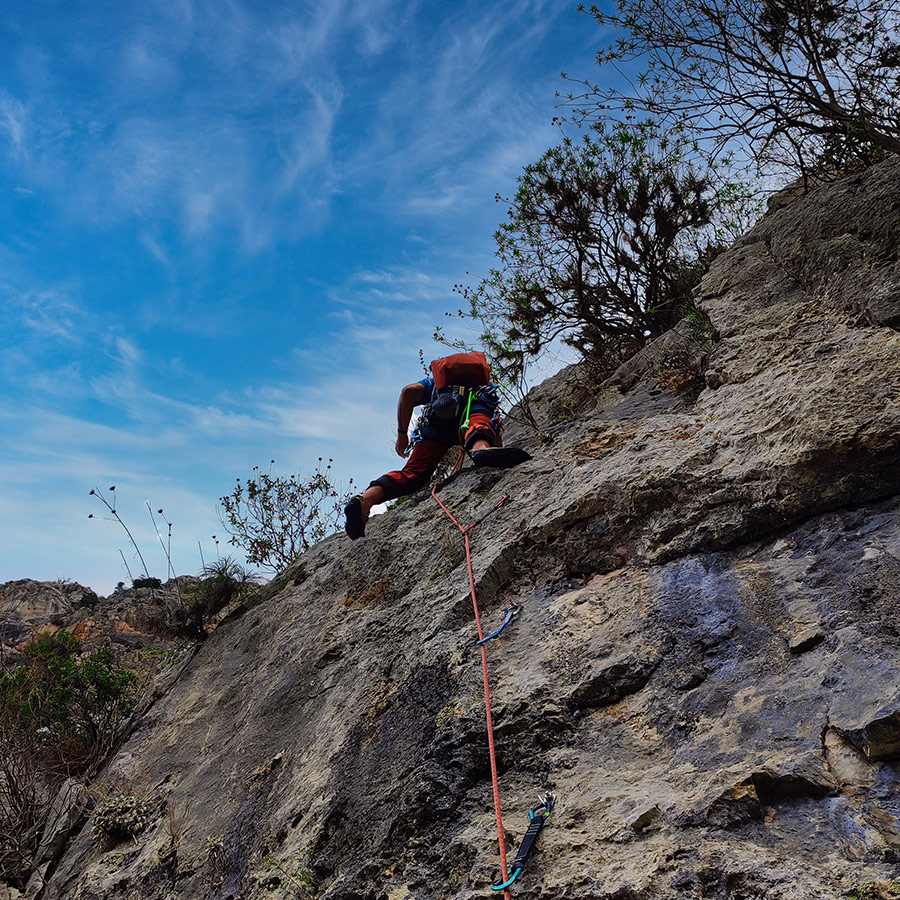 Climber leading on limestone slab section of Asterope multi-pitch climb, Pleiades Crag.