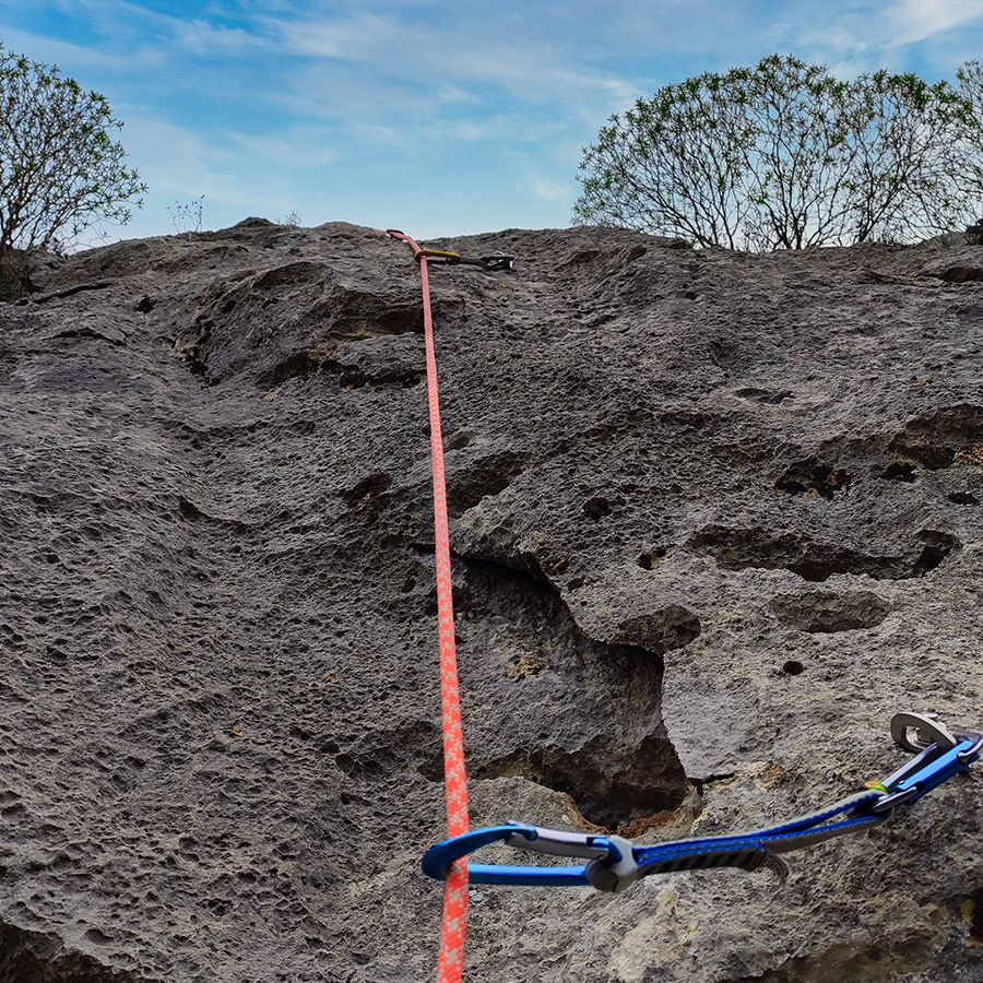 Climbing rope clipped into bolts on compact limestone section of Asterope route.