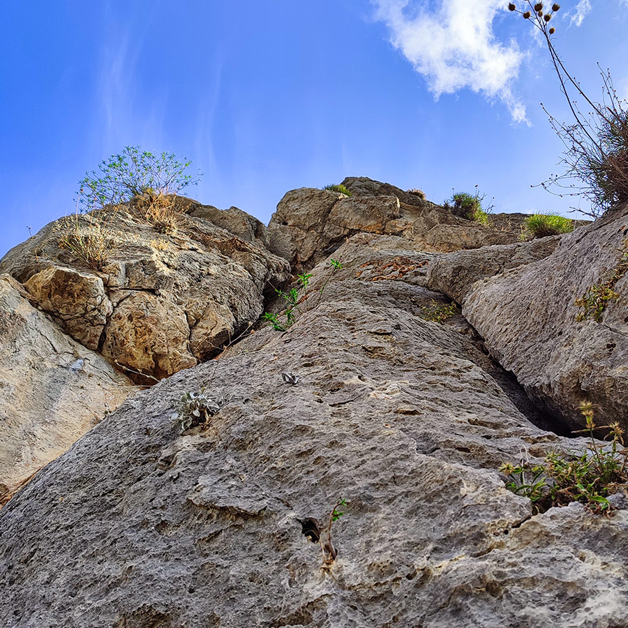 Limestone crack line of Asterope route at Pleiades Crag under a clear blue sky.