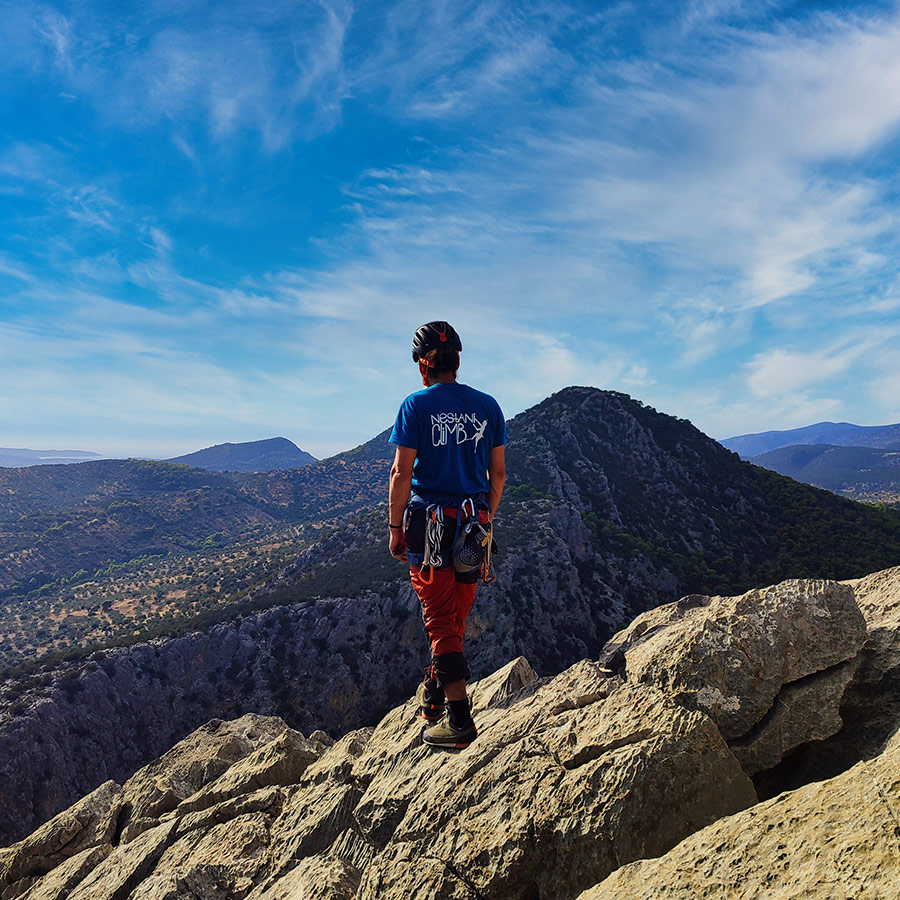 Climber standing at the top of Pleiades Crag overlooking Katafyki Gorge landscape.