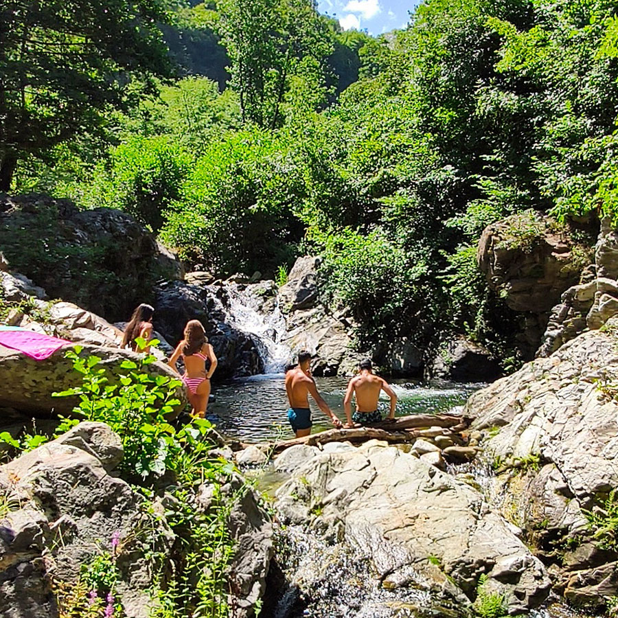 Visitors swimming at Kapejnci Waterfall natural pool in North Macedonia
