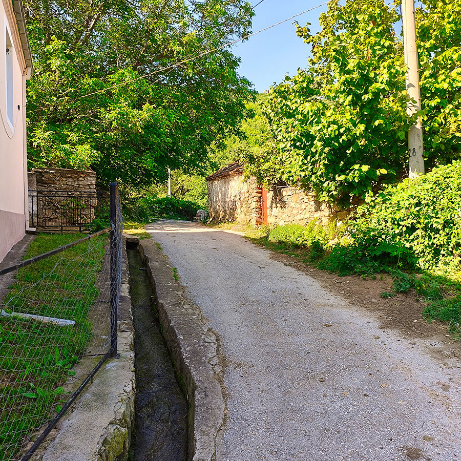 Village road in Capari with traditional stone walls and mountain scenery