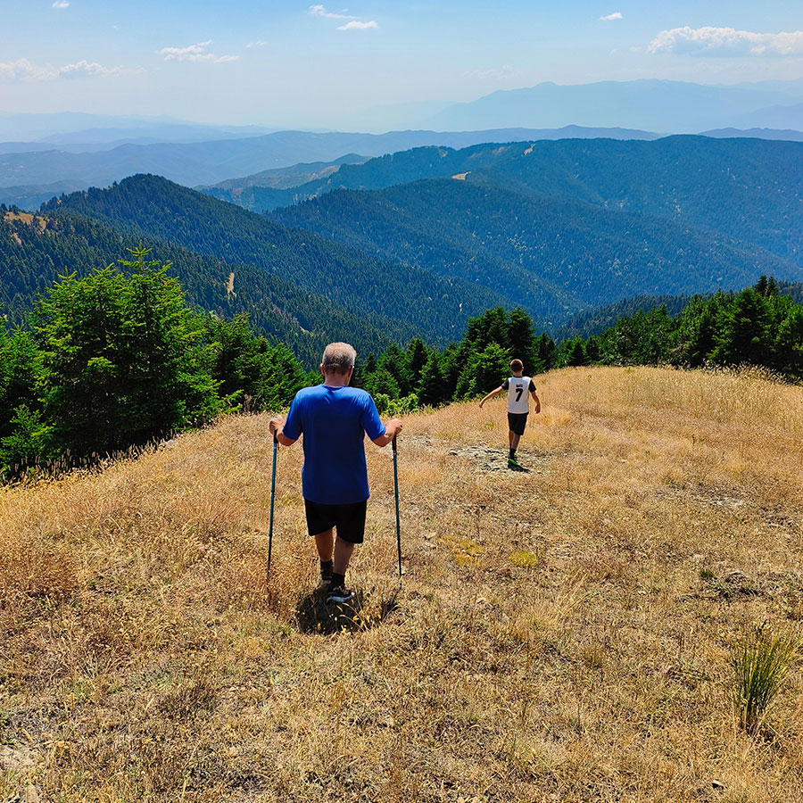 Hikers descending from Voulgara Peak across the alpine meadows of the Agrafa Mountains.